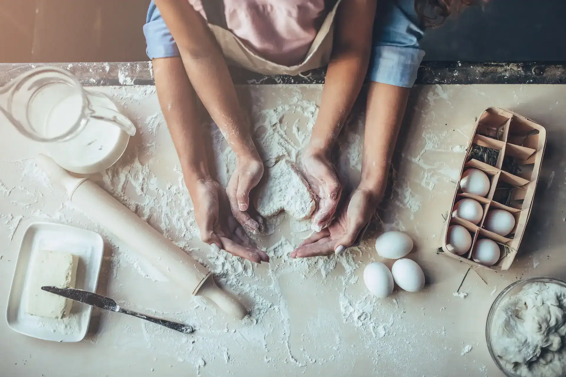 Baker with a kid making a heart with the dough