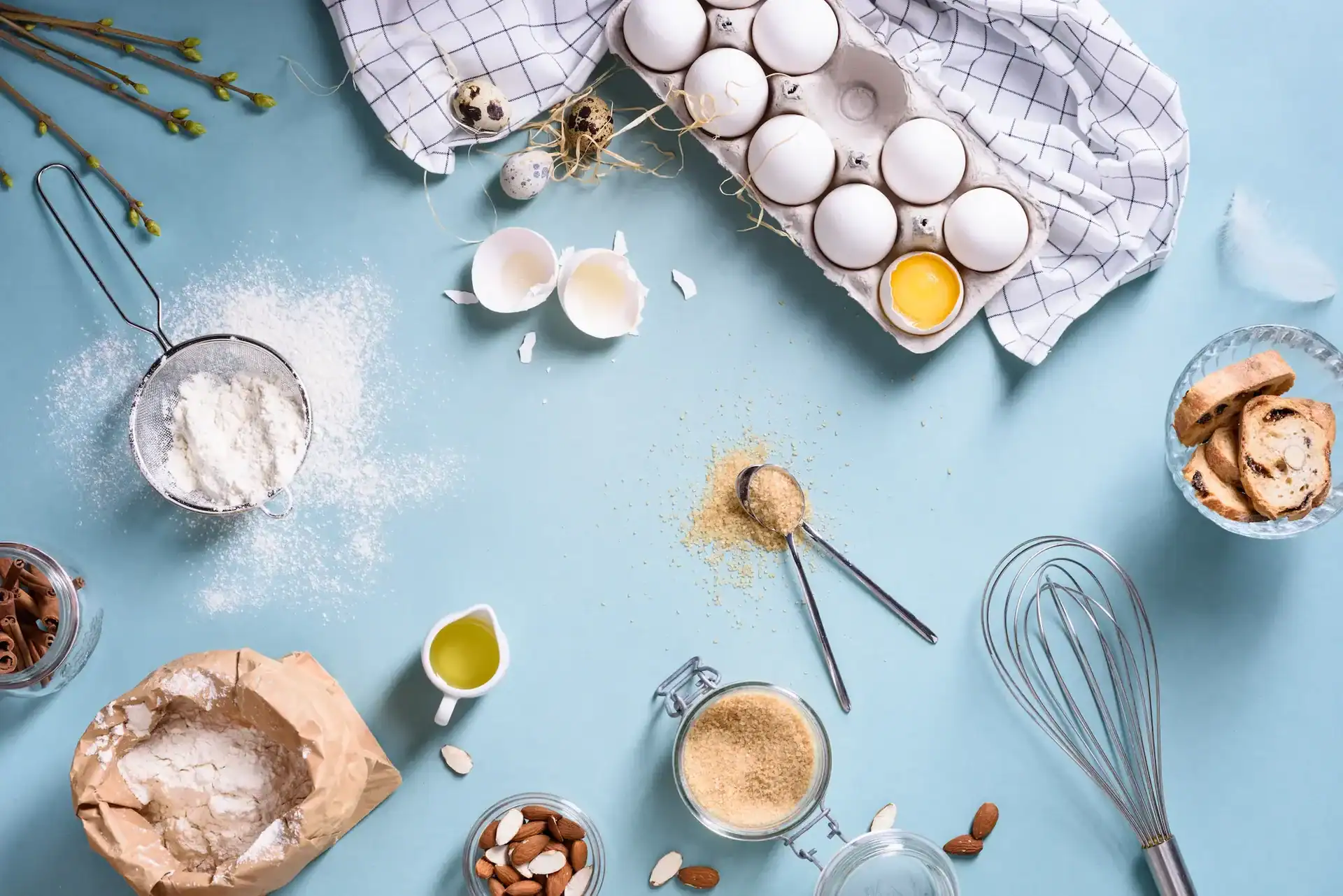 eggs, flour, whisks, and other bakery ingredients spread across a table