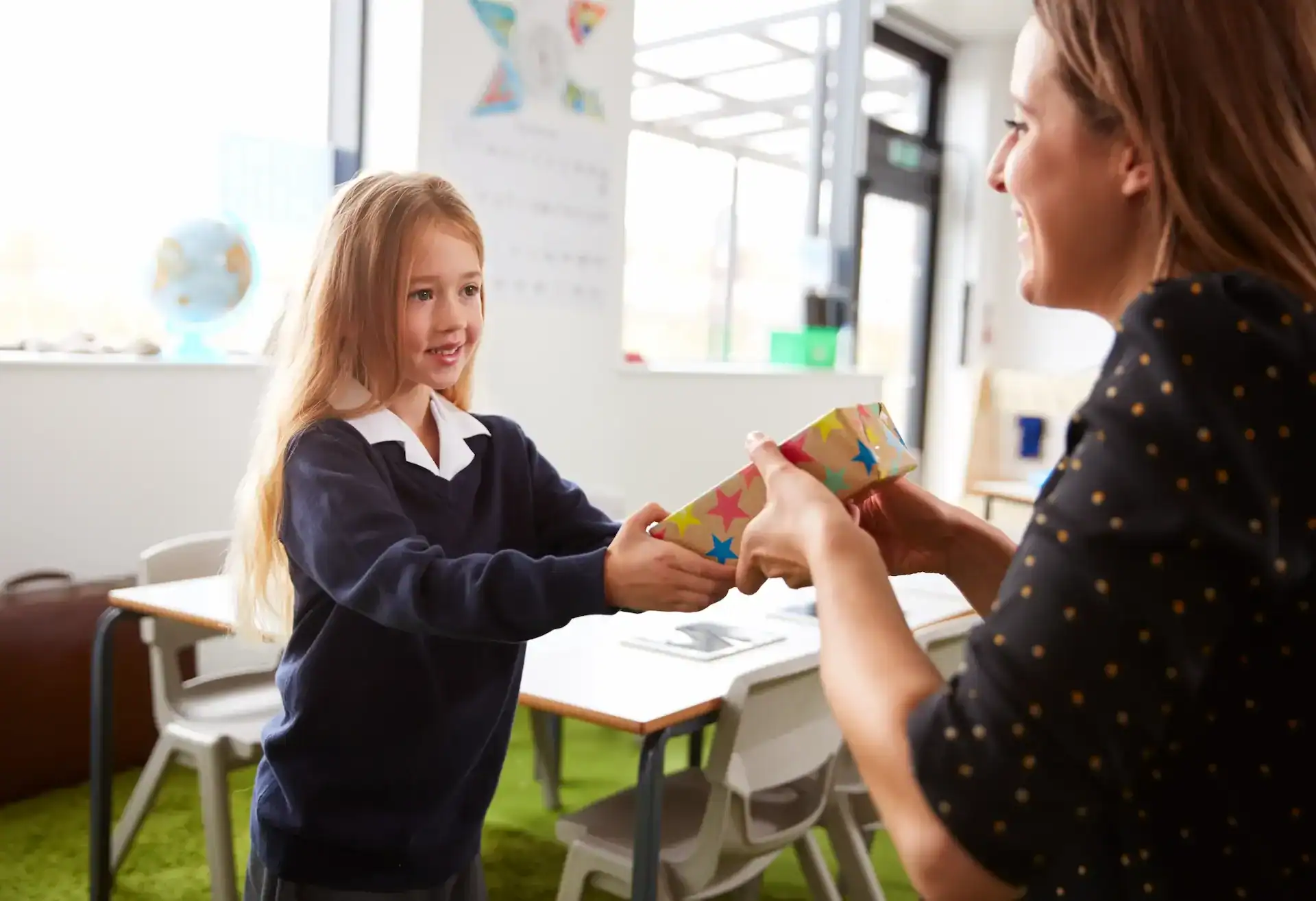 Young girl student handling a gift to her teacher