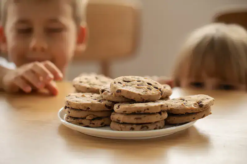 Two kids reaching for cookies
