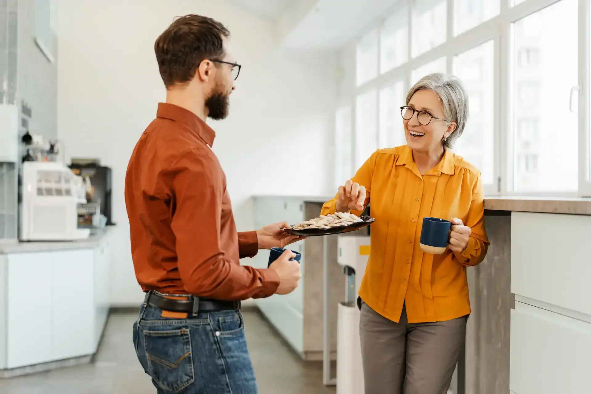Man handing and older lady teacher a plate of cookies